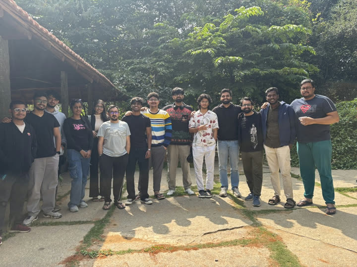 A big group of friends posing together outdoors under the trees